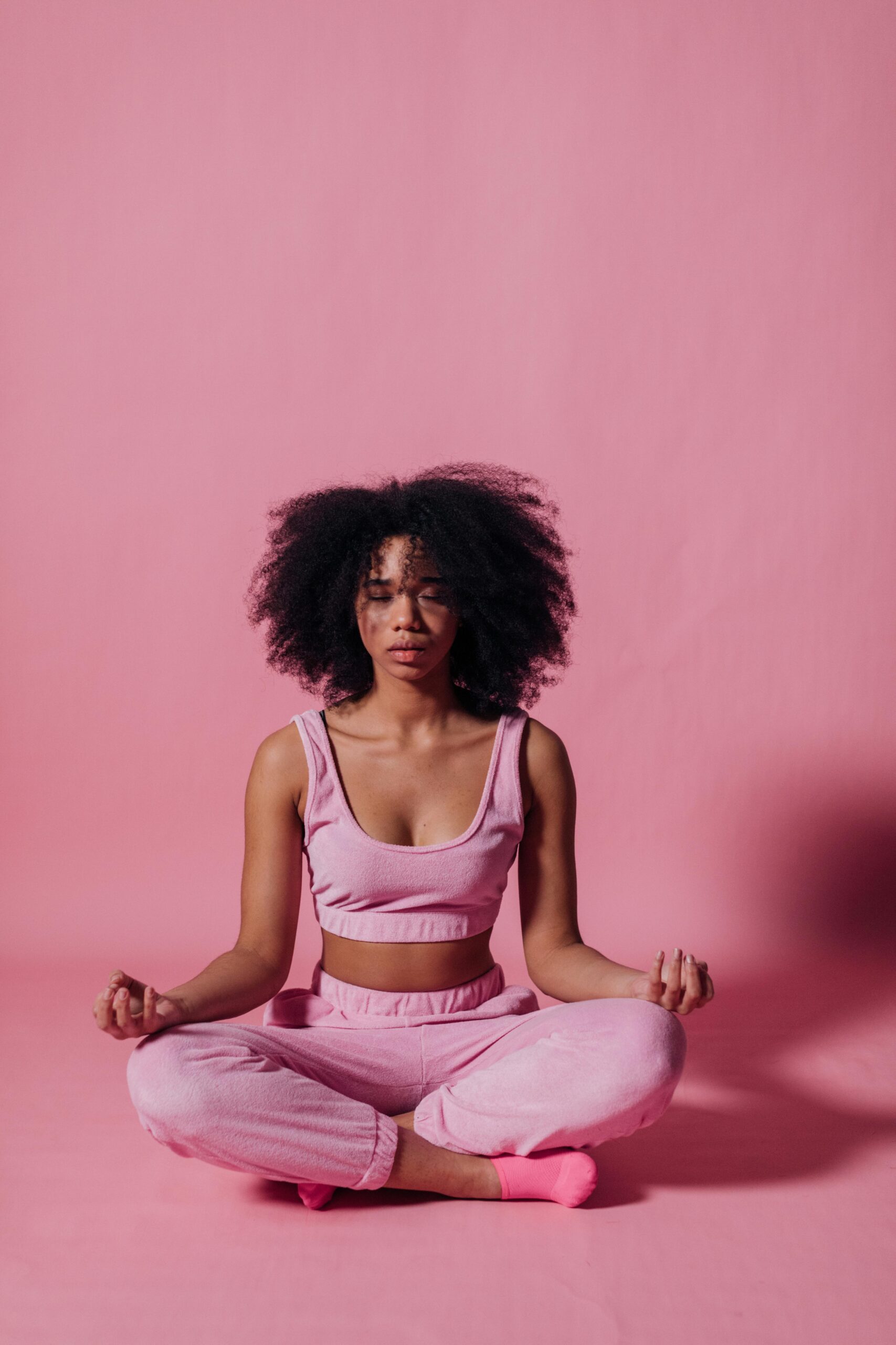Photo by KoolShooters : https://www.pexels.com/photo/woman-in-pink-crop-top-and-jogging-pants-practicing-yoga-7346634/